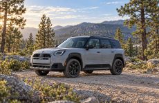 Grey MINI Countryman Untamed with a black roof parked on a rocky forest track.